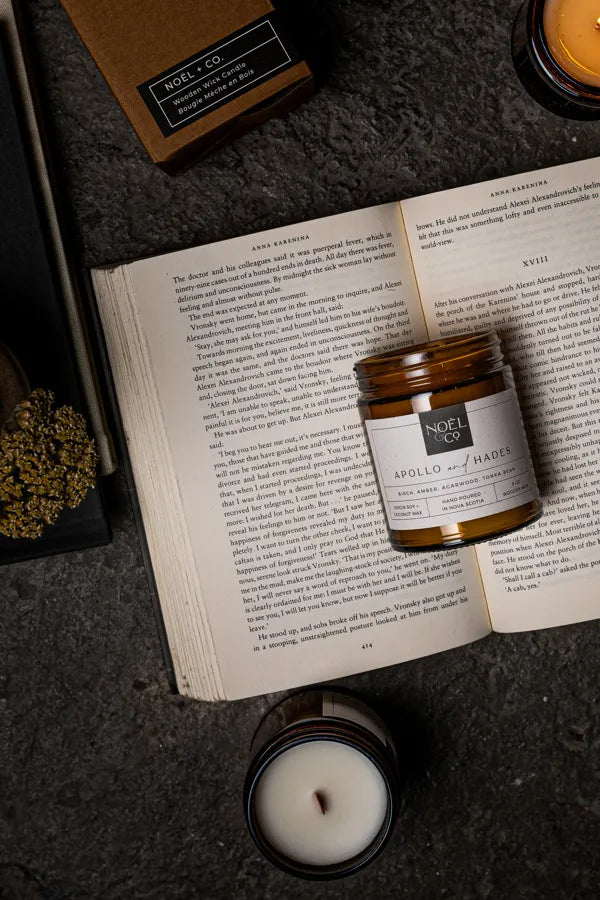 A candle with an amber glass jar laid on a book 