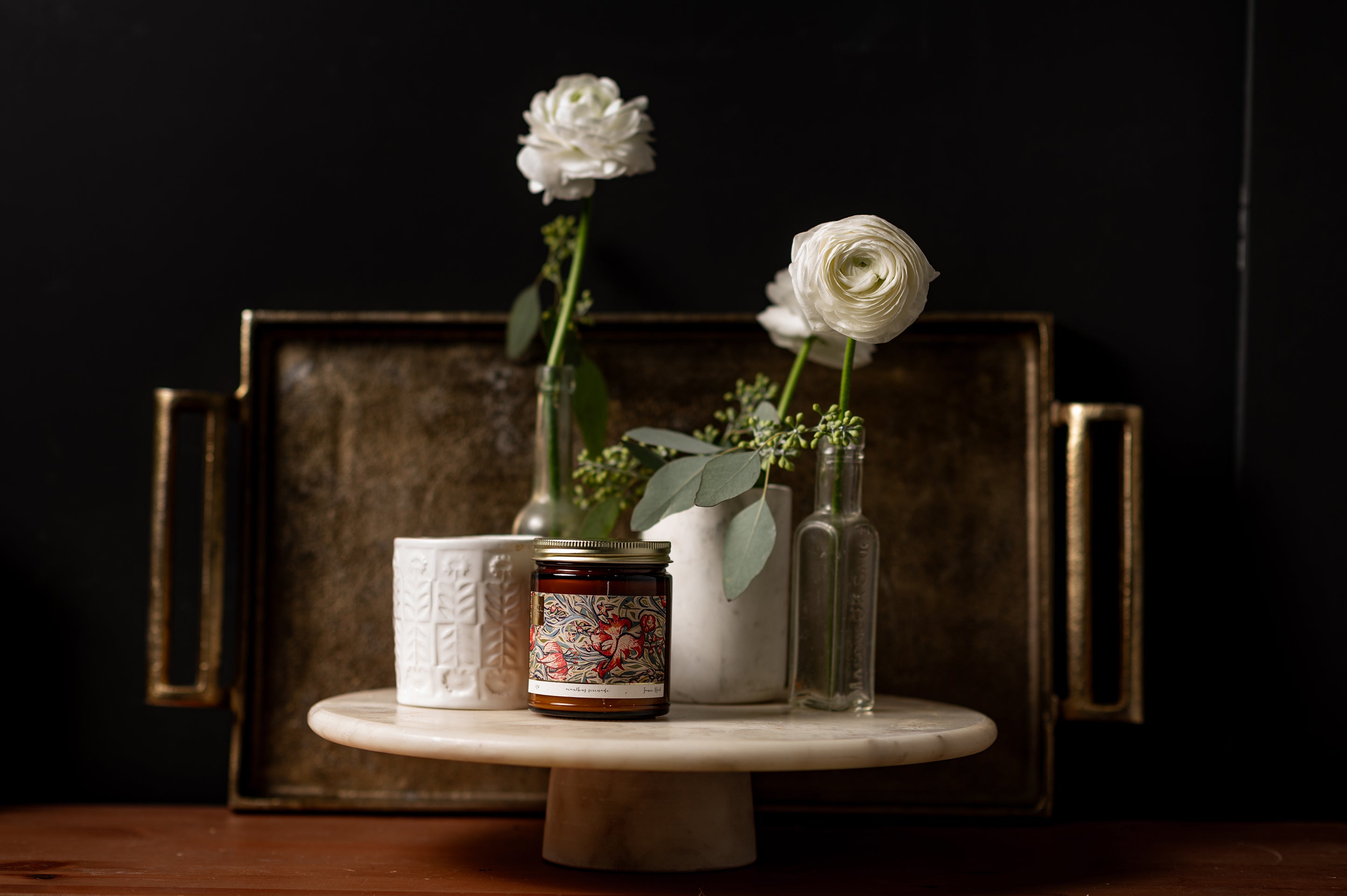 A candle in an amber glass jar with a original art piece featured on the label.