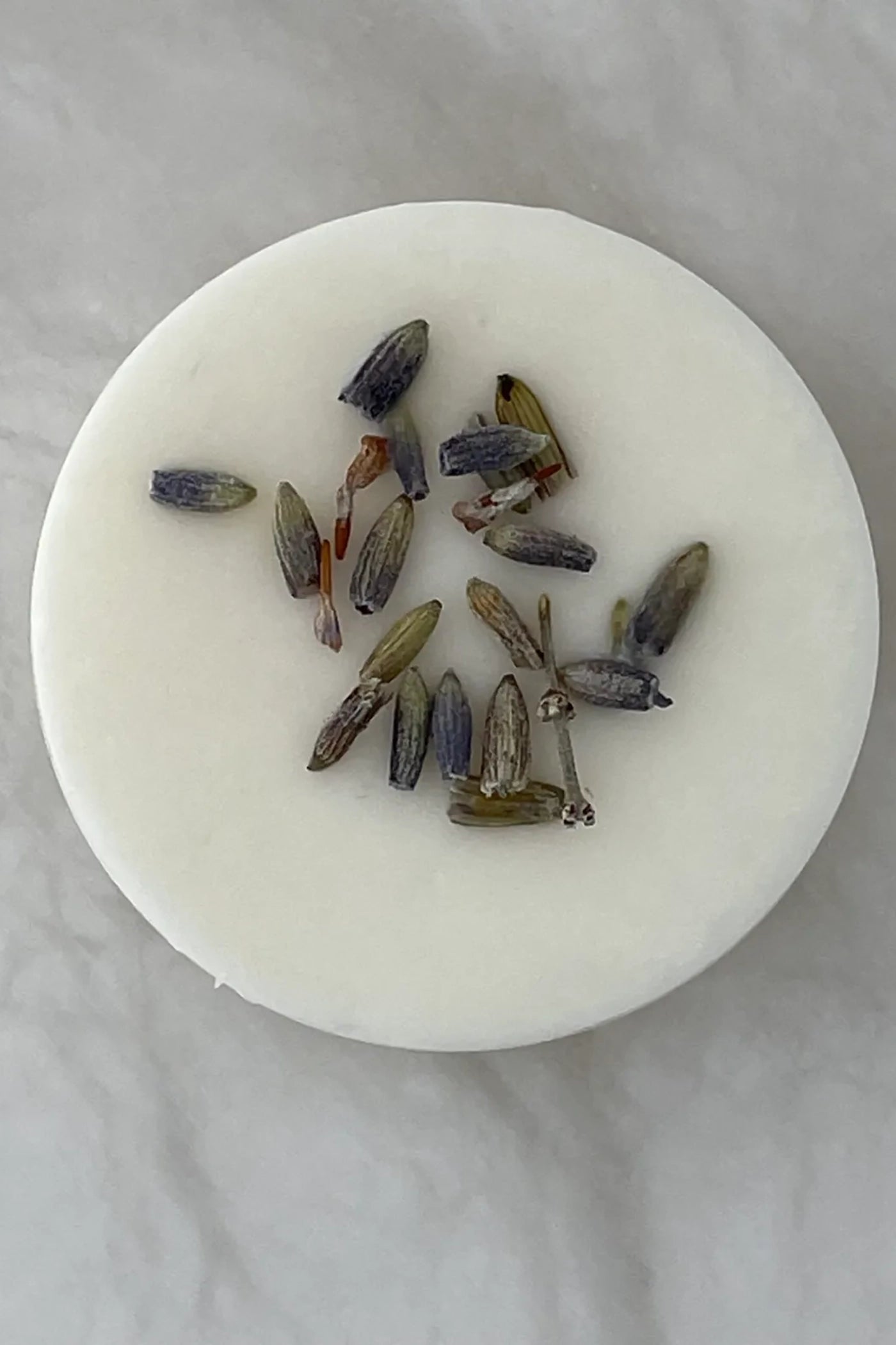 A single white wax melt with pieces from the scent profile in the wax.