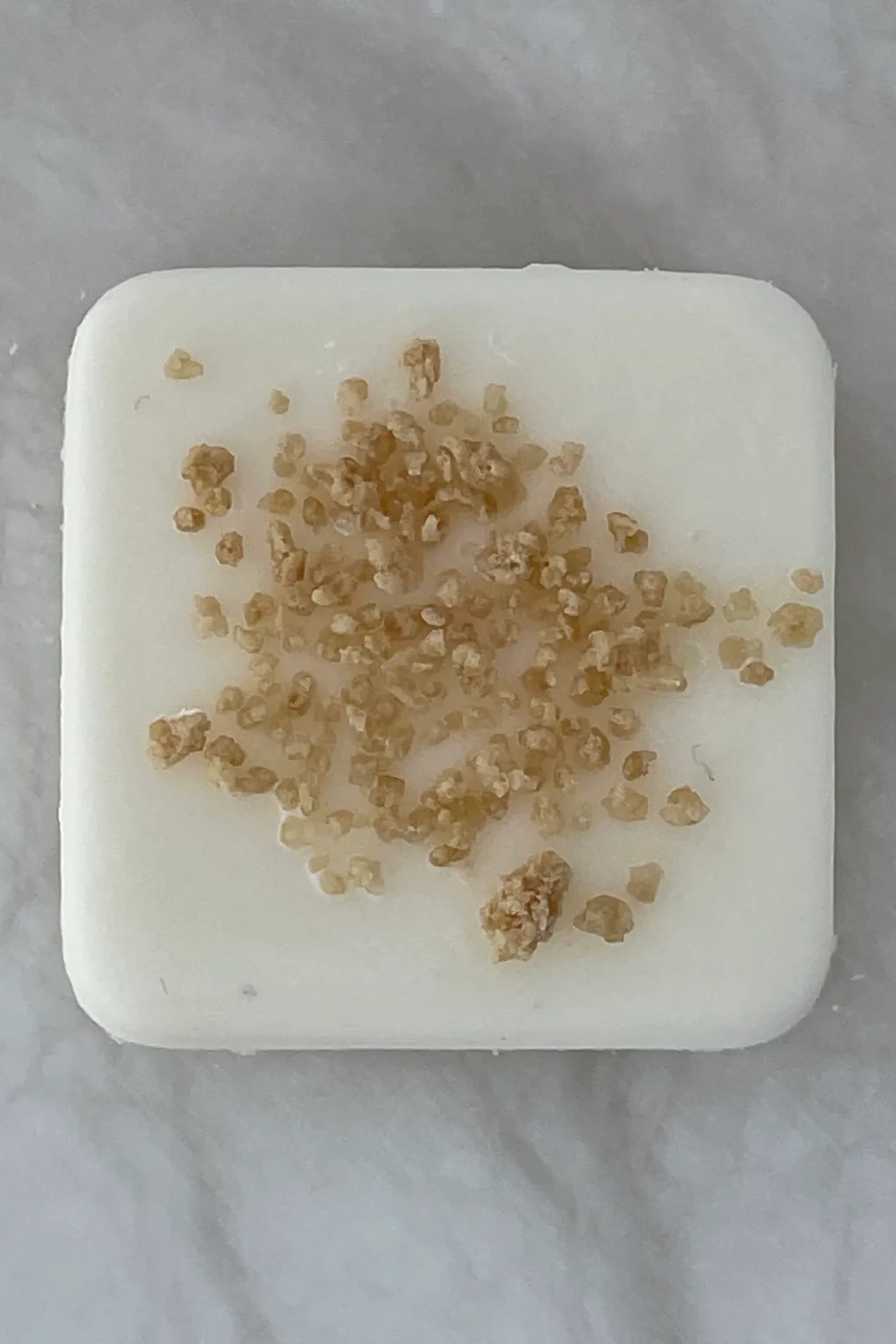 A single white wax melt with pieces from the scent profile in the wax.