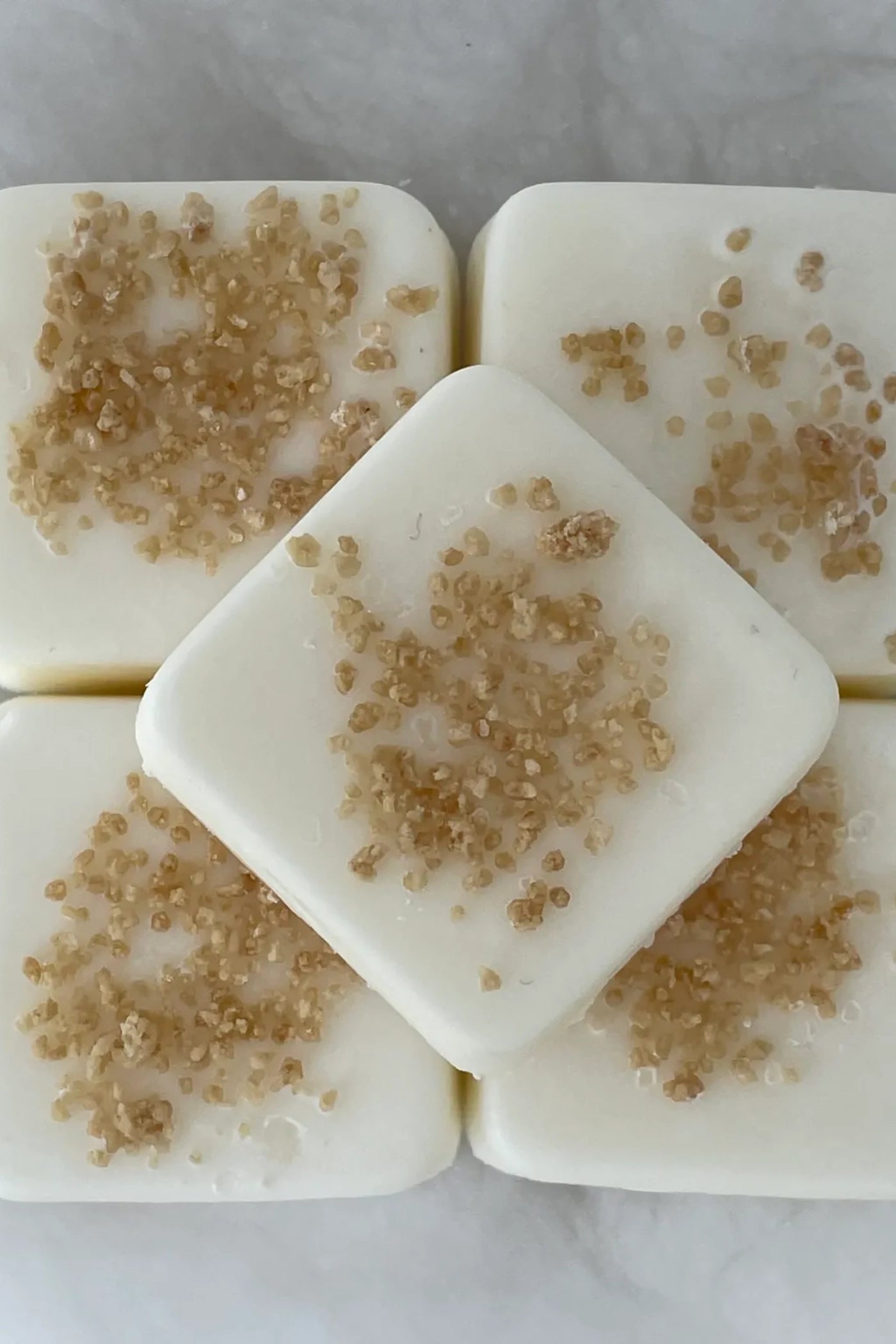 multiple white wax melts with pieces from the scent profile in the wax.