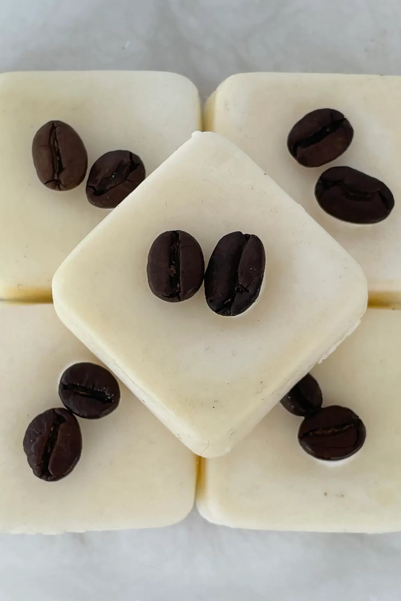 Multiple white wax melts with two coffee beans on top of each.