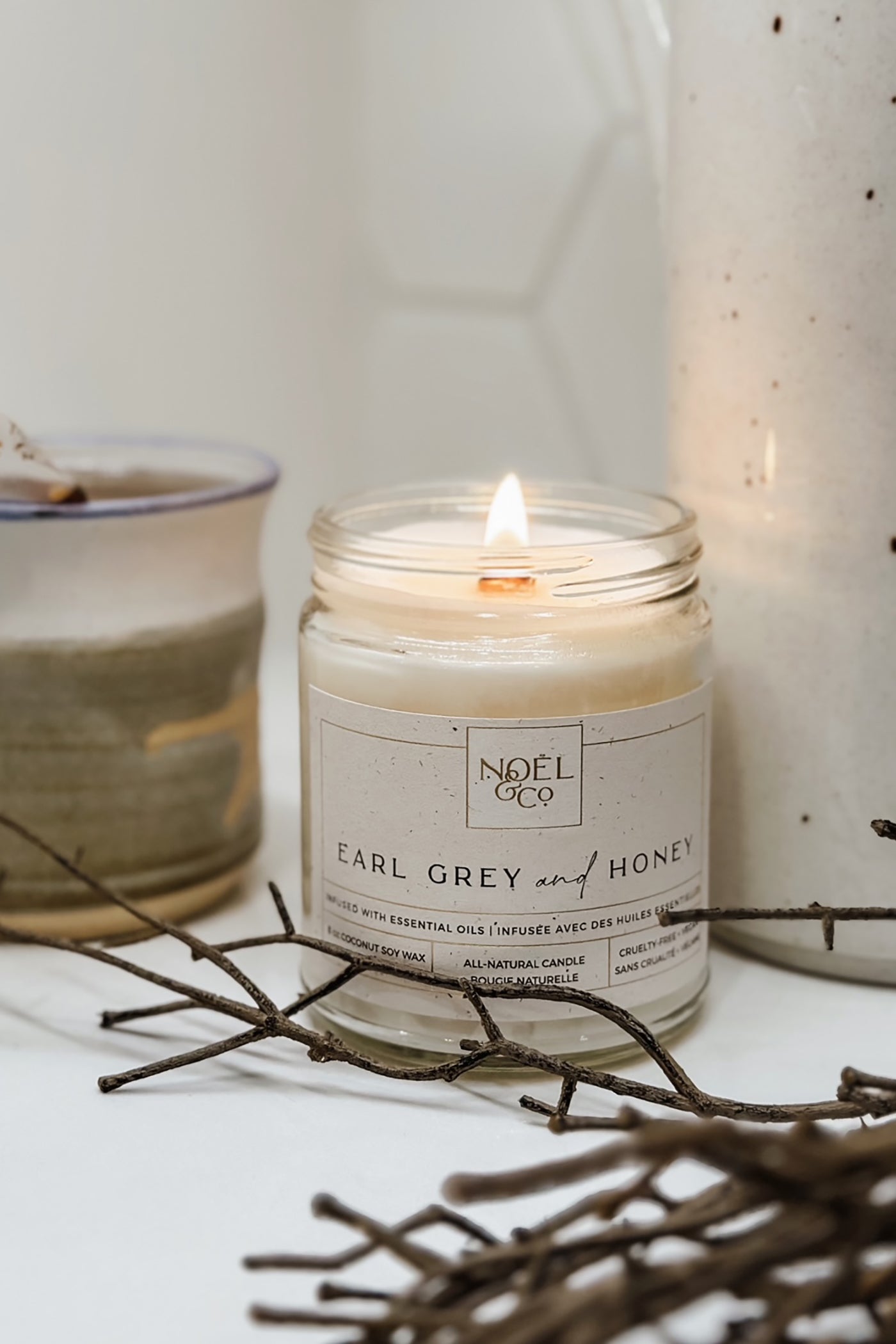 A lit candle in an clear glass jar with a wooden wick.