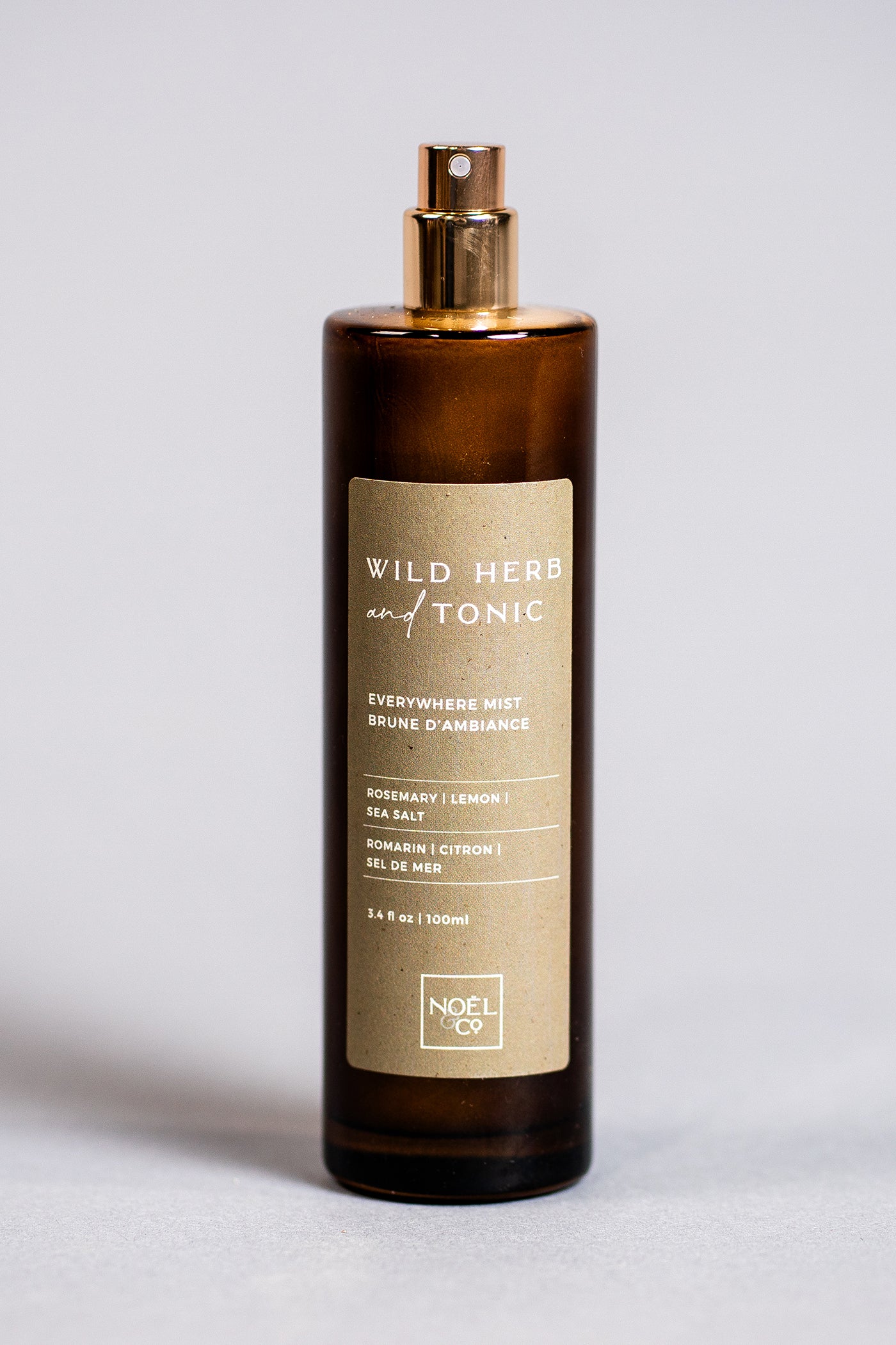 A Noel and Co bottle of 'Wild Herb & Tonic' everywhere mist spray with a green label and a gold-colored cap.