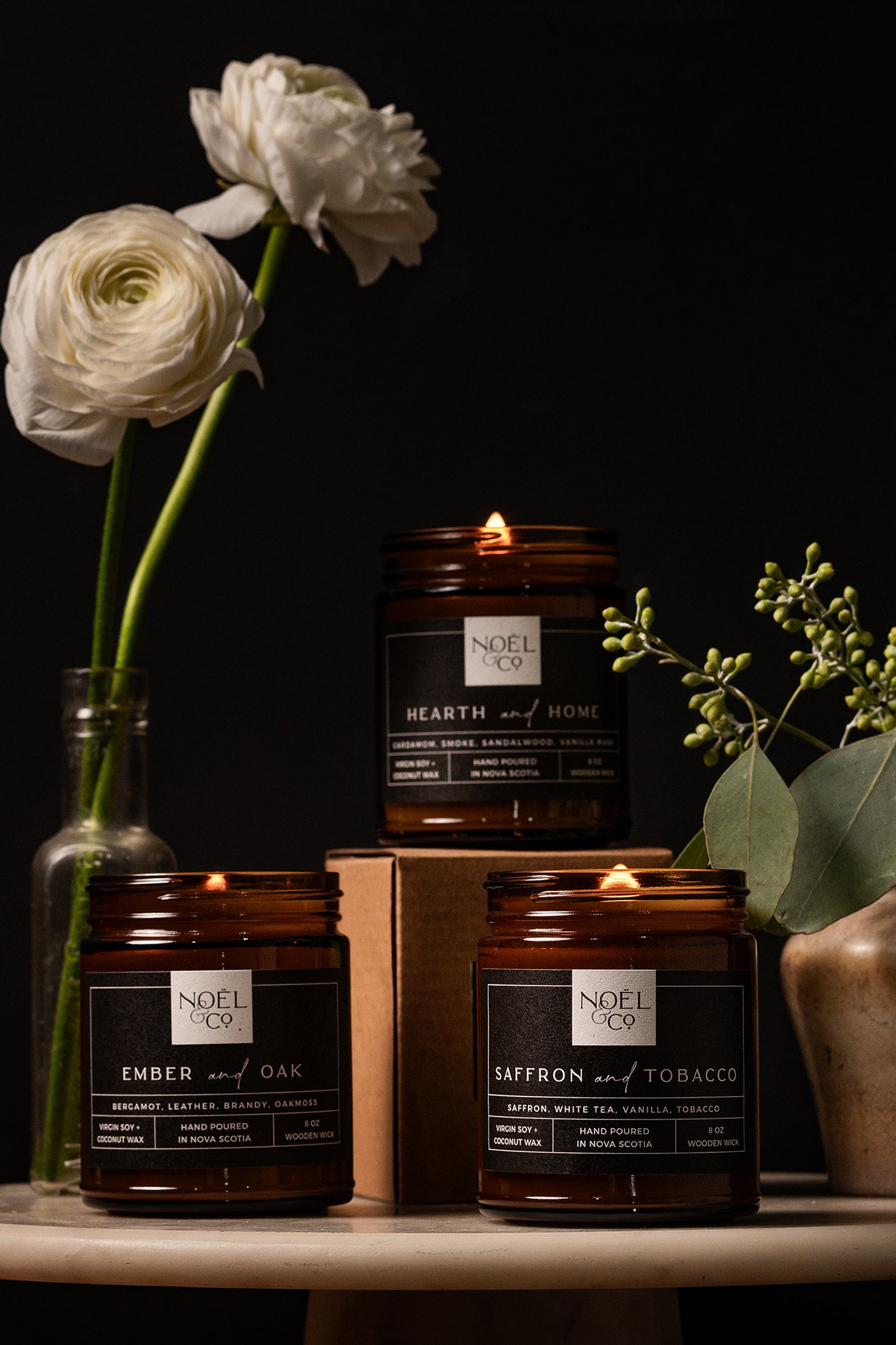 3 Noel and Co Noir Collection of candles on dark background with white flowers