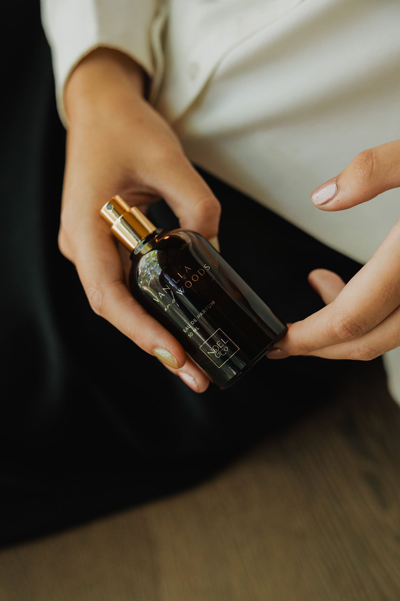 Person holding a Noel and Co perfume bottle with a blurred background