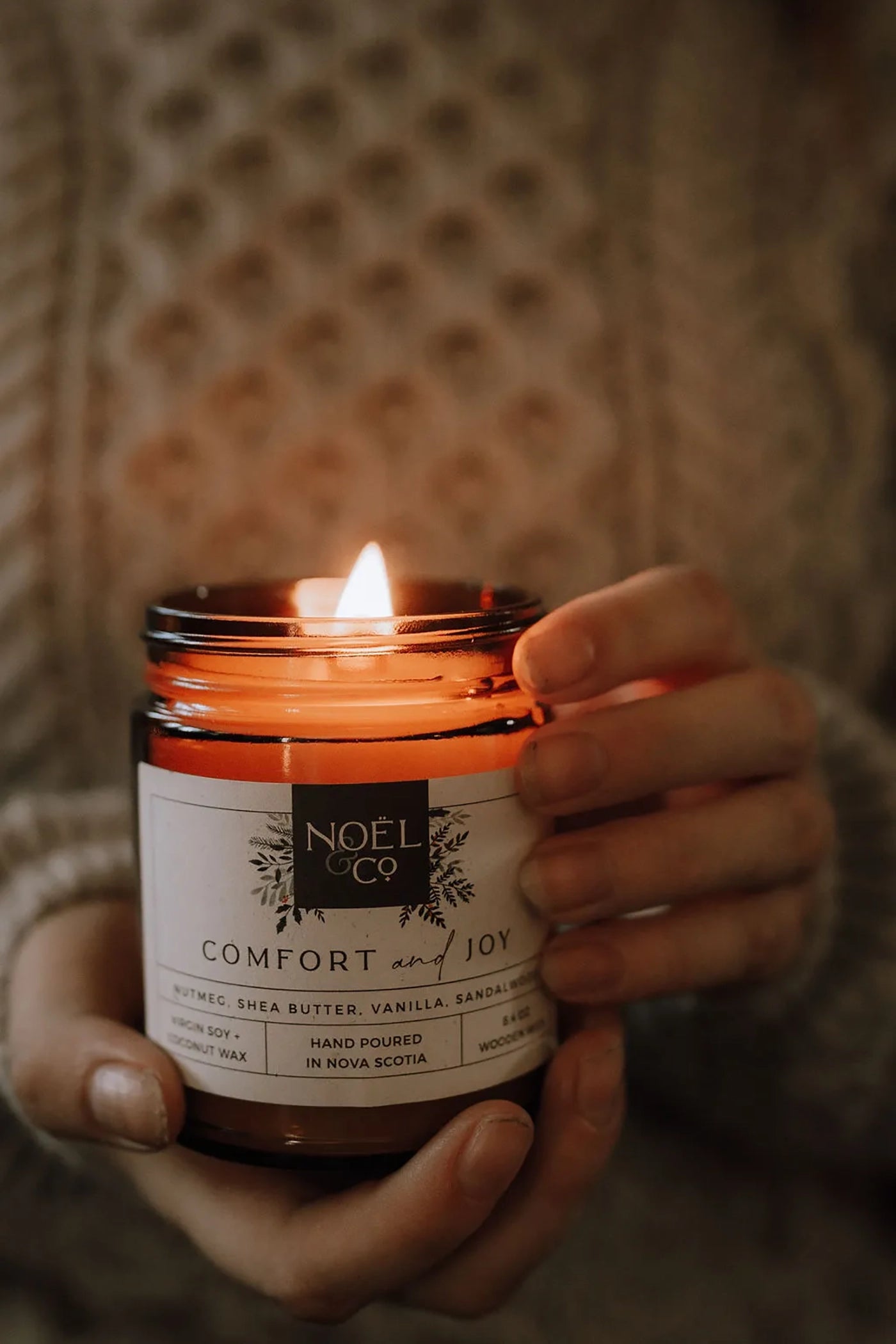 A lit candle in a amber glass jar.