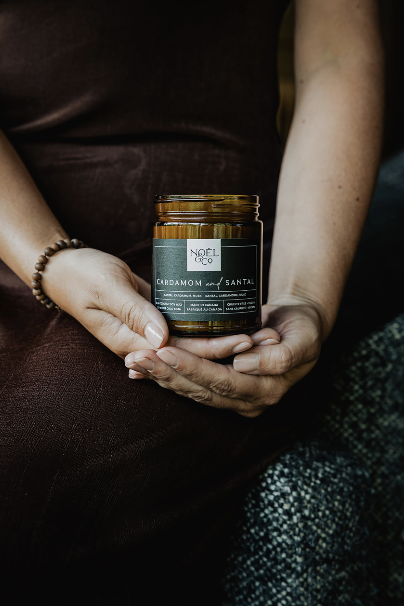 Person holding a jar of 'Noel & Co.' cardamom and santal candle.