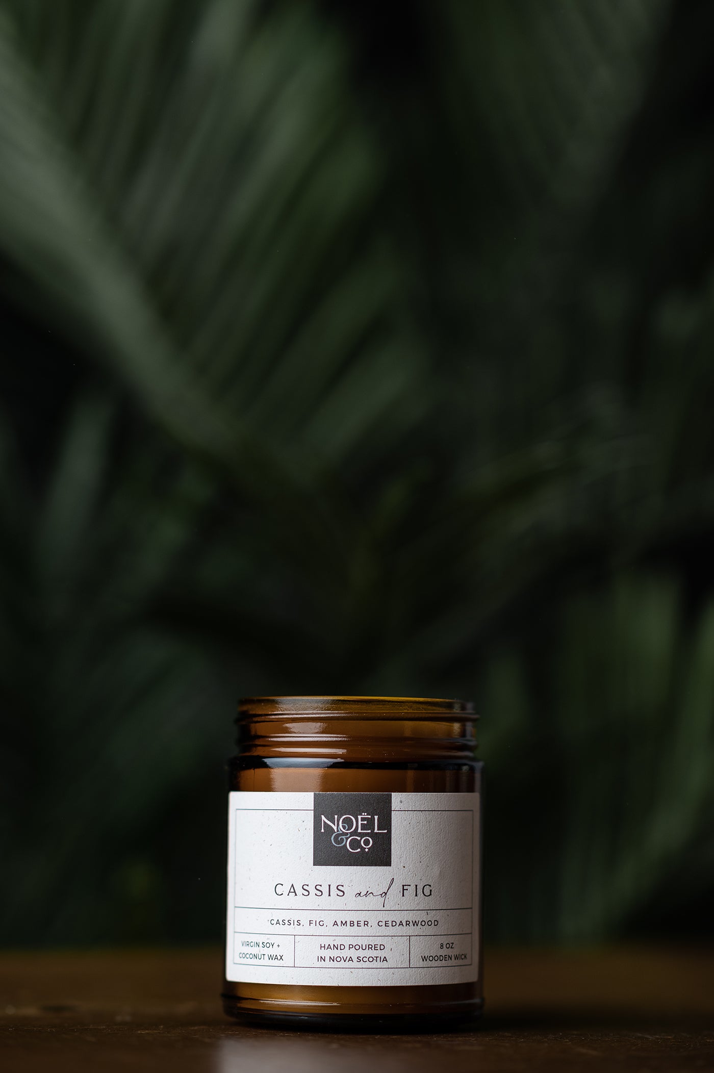 A Noel and Co candle in a amber glass jar.