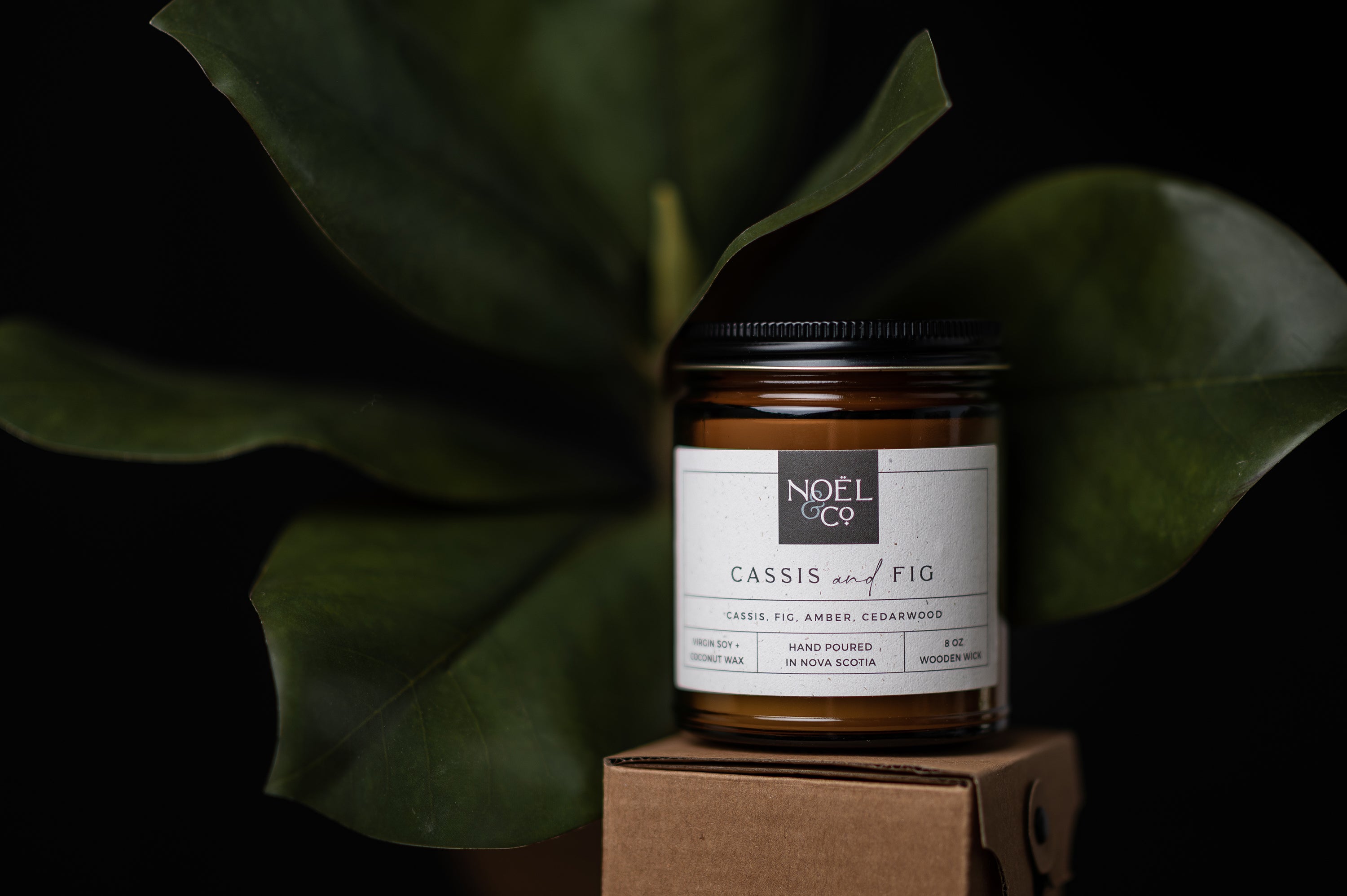 A Noel and Co candle in a amber glass jar.